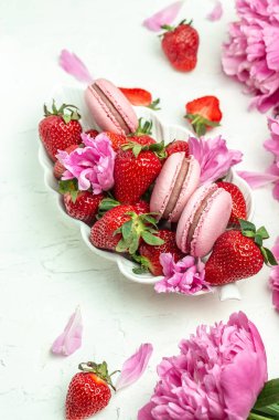 Pink peonies, sweet strawberry and macaron cookies dessert, on a white background. Banner, flyer, beautiful postcard, top view.