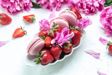 Elegant sweet macarons and Pink peony rose flowers, French delicate dessert on a white background. Long banner format. top view.