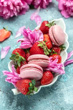 Delicious many peony flowers, macarons and sweet strawberry. Small French cakes with fruit, vertical image. top view,