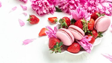 Delicious many peony flowers, macarons and sweet strawberry. Small French cakes with fruit,