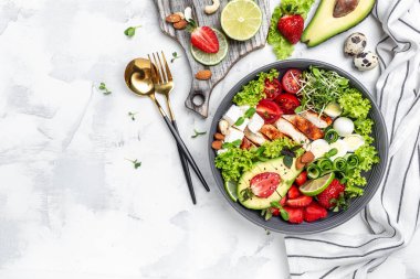 Avokado salatalı tavuk fileto, feta peyniri, bıldırcın yumurtası, çilek, fındık ve beyaz arka planda marul. Sağlıklı yemek, keto diyeti, diyet öğle yemeği konsepti. Üst görünüm.