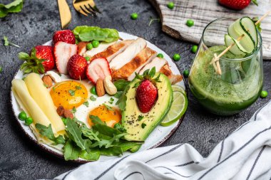 Sağlıklı düşük karbonhidratlı ürünler. Yağda yumurta, avokado, çilek, ızgara tavuk fileto, peynir, fındık ve roka, detoks smoothie, taze yeşil. Ketogenik diyet konsepti. en üstteki görünüm.
