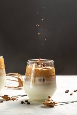 Dalgona kahvesi ya da çırpılmış kahve. Kore kahvesi hazır kahve ya da kremalı espresso tozu. Donmuş bir hareketle kahve dolduruyorum. dikey görüntü. en üstteki görünüm.