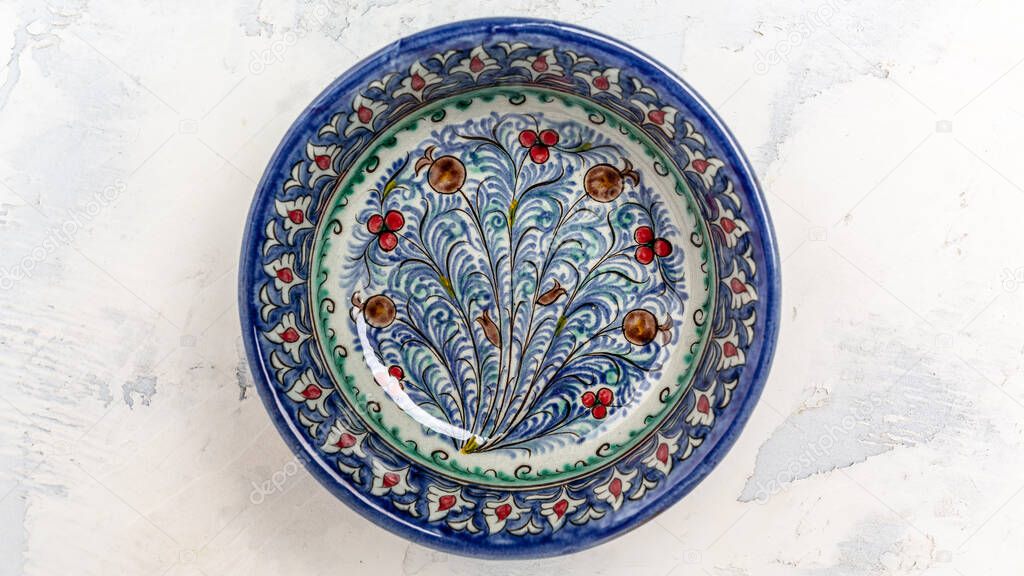 Ethnic Uzbek ceramic dish with white floral ornament in Central Asian style. Decorative ceramic with traditional uzbekistan ornament on a white background.