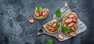Guacamole, çilek ve chia tohumlu kahvaltı tostu. Sağlıklı atıştırmalıklar. Çilekli avokado. Keto diyet tost. Vejetaryen sağlıklı gıda konsepti. Uzun afiş biçimi. en üstteki görünüm