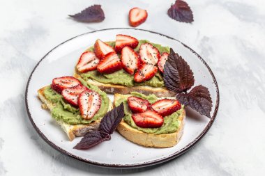 Avokado şeklinde tost, taze çilek ve tabakta chia tohumu. Vejetaryen sağlıklı gıda konsepti. Üst görünüm.
