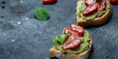 Guacamole, çilek ve chia çekirdekli tost. Sağlıklı yaz atıştırması. Vejetaryen sağlıklı gıda konsepti. Uzun afiş biçimi. en üstteki görünüm.