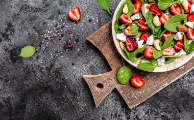 Bir kase çilekli salata, ıspanak yaprağı, fındık ve peynir, balzamik sirke. Detoks ve sağlıklı yiyecek kasesi konsepti.