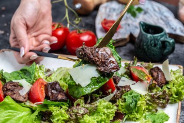 Kızarmış tavuk ciğeri, salata yaprakları, parmesan peyniri ve kiraz domatesli sıcak salata. Restoran menüsü, diyet, yemek kitabı tarifi..