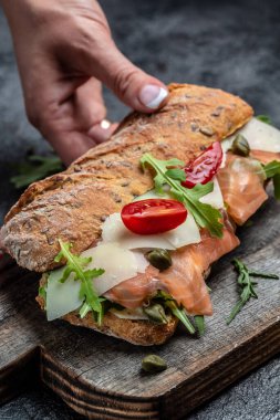 Sandviç, somonlu tost, krem peynir, parmesan peyniri, kapari, vişneli domates ve roka. dikey görüntü. en üstteki görünüm,