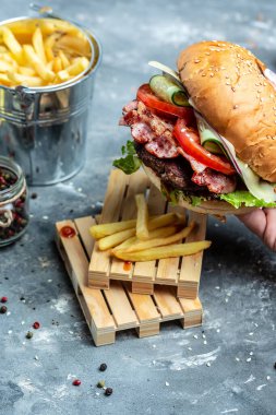 Elleri taze lezzetli hamburgerleri tutuyor. Pastırmalı hamburger ve köfte. Amerikan fast food 'u. Yemek tarifi geçmişi. Kapat..