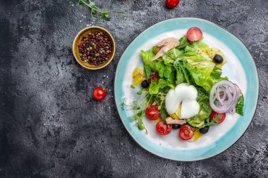 Haşlanmış ton balığı salatası, yumurta, marul, kiraz, domates zeytin ve mısır, koyu taş ya da beton arka planda. Üst Manzara. Boşluğu kopyala.