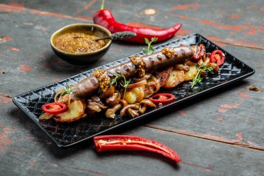 Biftek sosisi ve patates dilimleri kızartma tavasında kızartılmış yumurtalarla servis edilir.