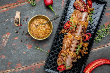 Biftek sosisi ve patates dilimleri ahşap arka planda acı biber ve hardalla servis edilir. afiş, menü, metin için tarif yeri, üst görünüm.