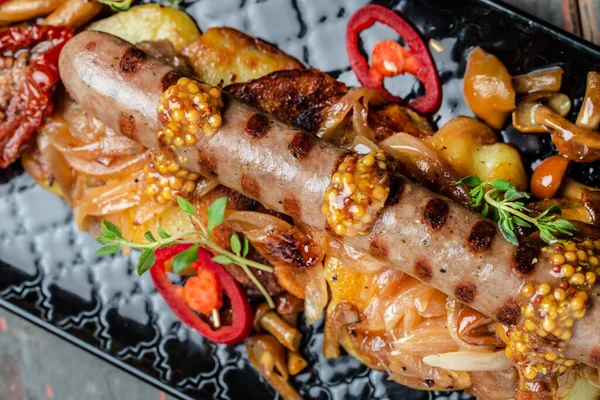 Sosisli patates, dilimlenmiş ve yağda kızartılmış, ahşap arka planda kırmızı biber ve hardalla servis edilmiş. Yemek tarifi geçmişi. Kapat..