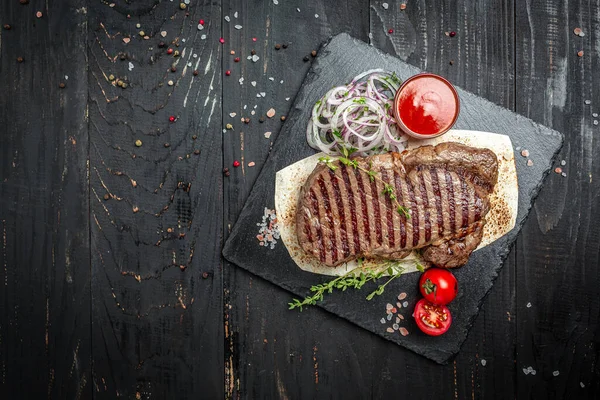 Medium rare grilled Steak Ribeye Black Angus with cherry tomatoes on wooden background, American meat restaurant. banner, menu, recipe place for text, top view.