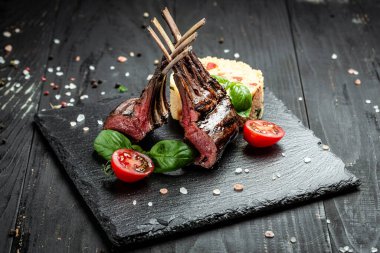 Ahşap arka planda fesleğen ve kiraz domatesli kuskus süslemeli kuzu askısı. afiş, menü, metin için tarif yeri, üst görünüm,