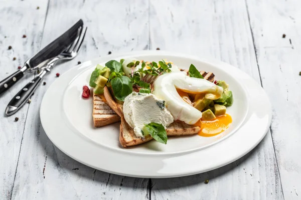 Kahvaltıda. Kızarmış ekmeğin üzerinde haşlanmış yumurta ve ahşap arka planda avokado tabağı. afiş, menü, metin için tarif yeri, üst görünüm.