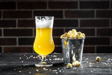 Glass of light beer with popcorn on wooden table, Snacks for beer. banner, menu, recipe,
