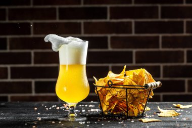 The beer style . Glass of beer and chips on wooden background. banner, menu, recipe place for text.
