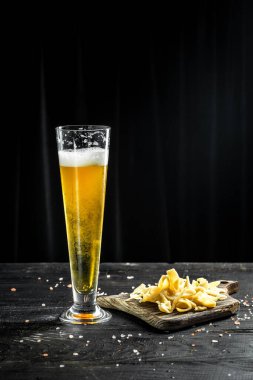 beer into a tall glass with Shredded Squid with pepper, fish snacks on wooden background. Beer brewery concept. Beer background.