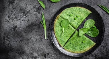 Lezzetli ıspanak krepleri siyah tabakta sebzeli yeşil krep, koyu arka plan, yemek tarifi geçmişi. Kapat.