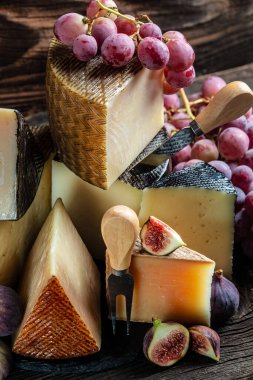 Çeşitli yumuşak ve sert peynirlerden oluşan peynir tahtası. İspanyol manchego peyniri, uluslararası süt ürünleri. dikey resim.