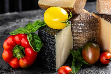 Domatesli ve fesleğenli sert peynirler. Geleneksel İspanyol, Fransız, İtalyan peyniri parçaları.