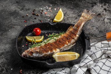 Izgarada domates ve limonla ızgara yapılmış nehir alabalığı. Sağlıklı beslenme eğilimi. en üstteki görünüm.