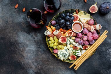 İtalyan atıştırmalıkları ve bardakta şarap olan aperatifler. Peynir, jambon, fındık, meyve, ekmek çubukları. Lezzetli dengeli gıda konsepti.