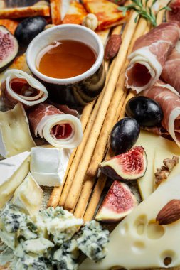 Peynir tabağı. Peynirin aperatifleri prosciutto, bal, fındık ve üzüm kesme tahtasında.,