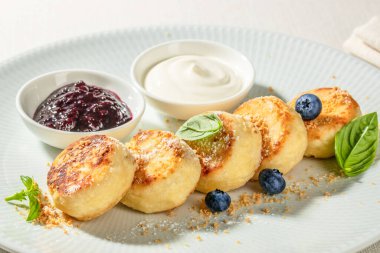 Ekşi krema, yabanmersini reçeli ve hafif bir tabakta taze böğürtlenli ev yapımı peynirli krep..