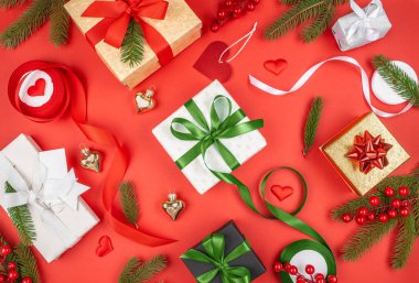 Kırmızı arka planda kırmızı, yeşil, altın ve beyaz kurdelelere sarılı, köknar dalları, böğürtlenler ve süslemelerle süslenmiş renkli hediye kutuları vardı..