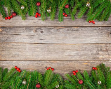 Köknar dalları, kırmızı böğürtlenler ve rustik ahşap yüzeyde mücevherlerle Noel arkaplanı, bayram kutlamaları veya afiş tasarımı için fotokopi alanı olan şenlikli üst görünüm kompozisyonu