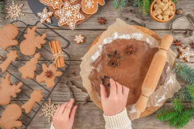 Noel kurabiyesi yapma sürecinde zencefilli ekmek hamurundan şekiller kesilir. Köy ahşap masa üzerinde kesiciler kullanılır. Köknar dalları, baharatlar ve süslü kurabiyeler ile bayram pişirme konsepti.