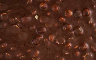 Close-up texture of dark chocolate with whole nuts, detailed background perfect for dessert branding, packaging design, and confectionery advertising