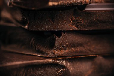 Dark chocolate bars stacked in a close-up macro shot showing rich texture and rustic details, ideal for confectionery advertising, packaging design, and premium dessert branding