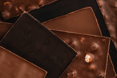 Katmanlı koyu renkli, sütlü ve fındıklı çikolatalardan oluşan yakın çekim, fotokopi alanı olmadan sıcak makro ışıklandırmaya yakalanmış, şekerleme reklamcılığı için ideal, tatlı markalaşması.,