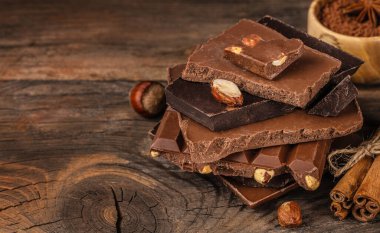 Kırsal ahşap arka planda fındıklı çikolatalar yığını yiyecek reklamcılığı ve tatlı ürün markalaşması için mükemmel sıcak ve rahat bir tatlı atmosferi yaratıyor..