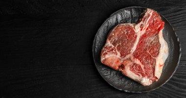 Siyah bir seramik tabakta taze çiğ biftek. Fotokopi alanı, restoran menüsü, kasap dükkanı, et reklamcılığı ve markalaştırma için ideal.