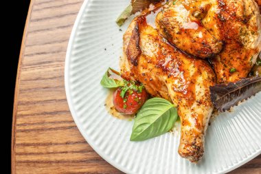 Kızarmış tavuk budu, çıtır çıtır altın ten, taze otlar ve ahşap zemin üzerinde servis edilen kiraz domatesi..