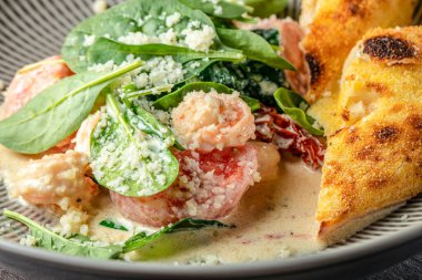 Krem soslu gurme karides, taze ıspanak, otlar ve restoran tarzında seramik tabakta kızarmış ekmek..