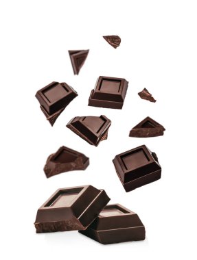 Havada yüzen ve aşağıda istiflenmiş siyah çikolata parçaları, beyaz arka planda izole edilmiş, modern reklam ve ambalaj tasarımı için fotokopi alanı ile kaliteli tatlı konsepti.