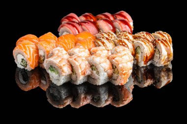 Somon, karides ve yılan balığı soslu çeşitli suşi dürümleri. Japon mutfağı siyah arka planda yansımalı, kaliteli restoran yemeği konsepti.