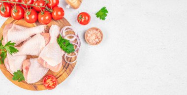 Tahtaya yerleştirilmiş çiğ tavuk budu taze domatesler, soğan halkaları, maydanoz ve tuz fotokopi alanı, üst görünüm