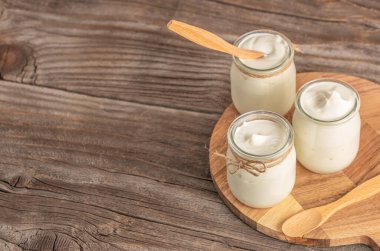 Küçük cam kavanozlarda laktoz içermeyen yoğurt fotokopi alanı, sağlıklı sindirim ve süt ürünleri konsepti ile sade ahşap arka planda düzenlenmiştir.