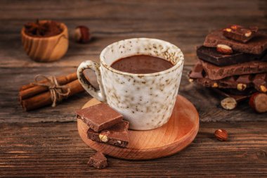 Sıcak ev yapımı sıcak çikolata seramik bir bardakta tarçın çubukları ve fındık çikolatalı, sıcak bir tatlı sahnesi olarak tasarlandı.