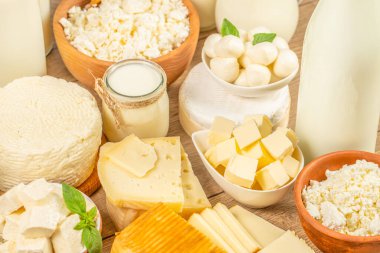Peynirler, tereyağı, mozzarella topları ve kırsal mutfak tarzında ahşap masaya yerleştirilmiş süt içeren çeşitli taze süt ürünlerinin yakın plan çekimi.