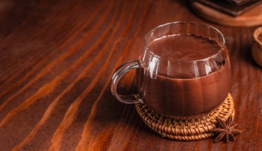 Kırsal ahşap masa üzerinde cam bardak sıcak çikolata, dokuma makinesinde baharatlarla servis edilir, reklam ve menü tasarımı için fotokopi alanı ile rahat bir içecek sahnesi yaratır.