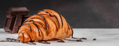 Fotokopi masası üzerine koyu çikolata serpiştirilmiş taze kruvasan, reklam ve markalaşma için fırın tatlı konsepti.